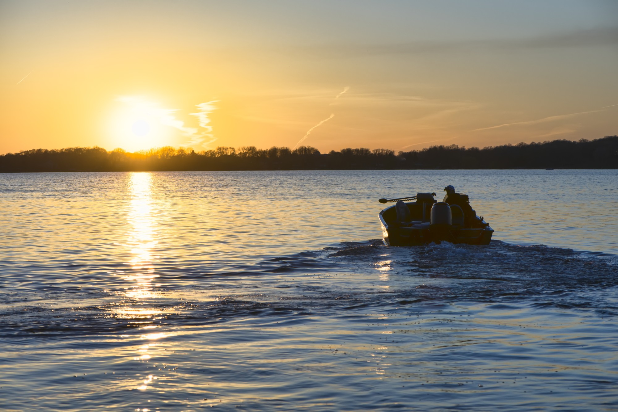Image of a boat driving away during sunset.