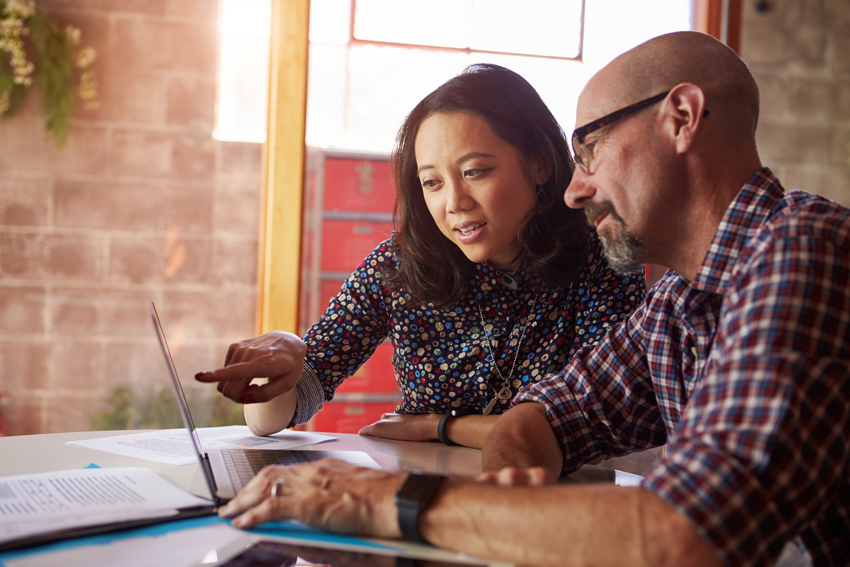 Woman and man sitting at a desk looking at a laptop