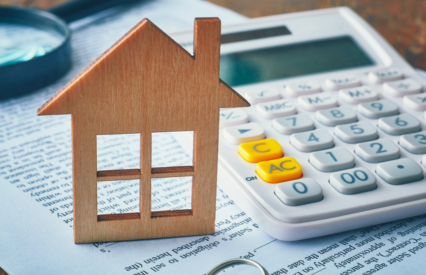 A wooden house cutout next to a calculator
