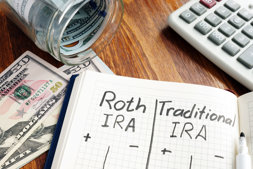 Jar of money, notebook with IRA notes, and a calculator on a desk