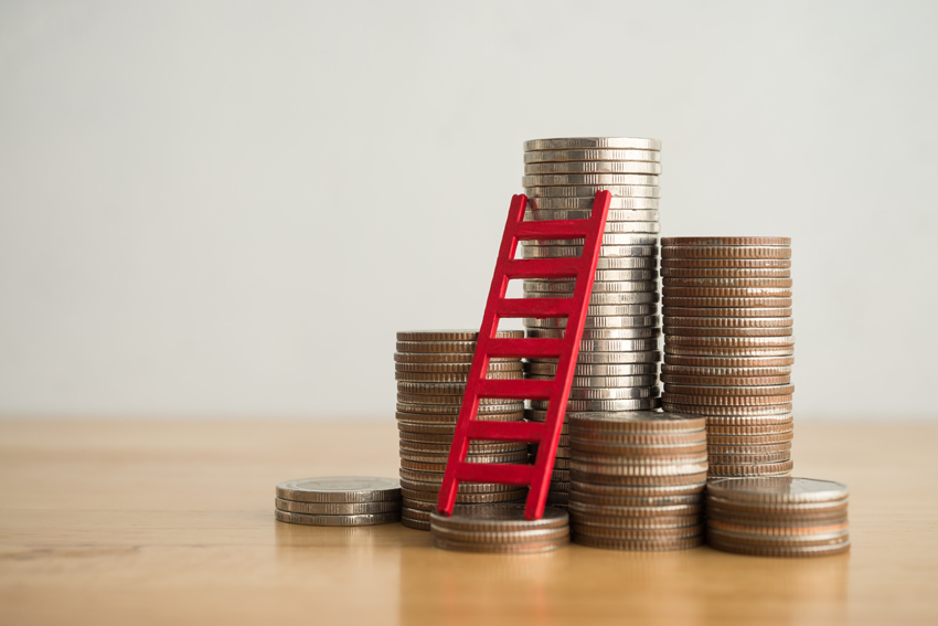 Toy ladder leaning on stacks of coins