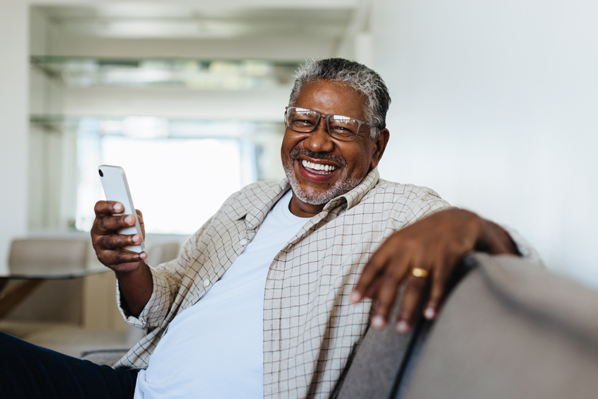 Senior man on sofa holding a phone
