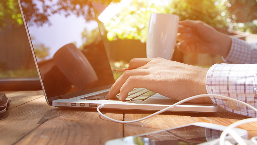Person working on a laptop outdoors at sunrise